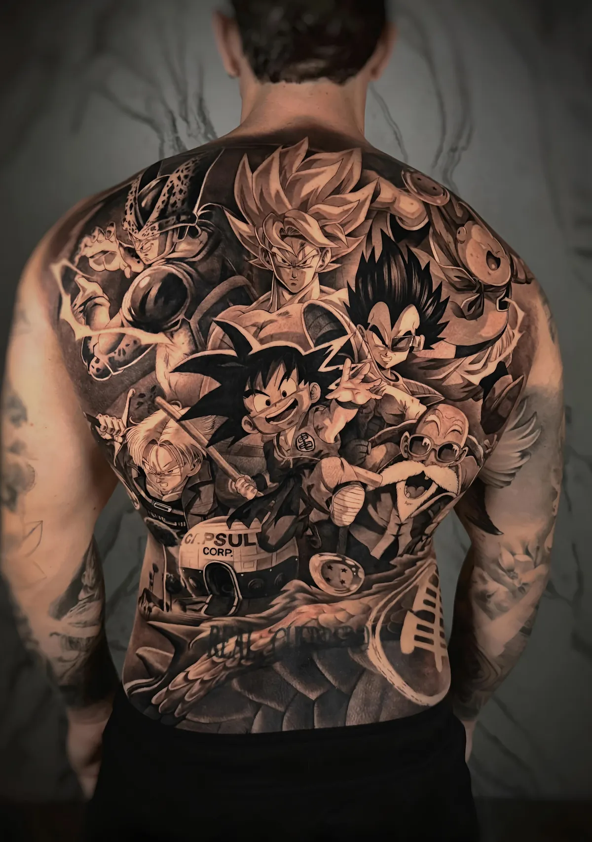Espalda completa tatuada con personajes de Dragon Ball en estilo anime realista